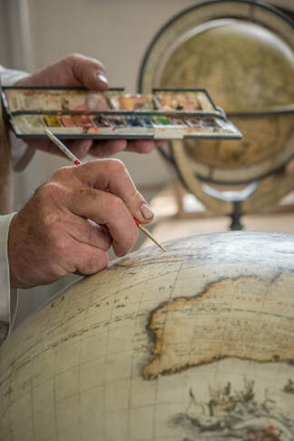 hand painting a Coronelli globe under restoration