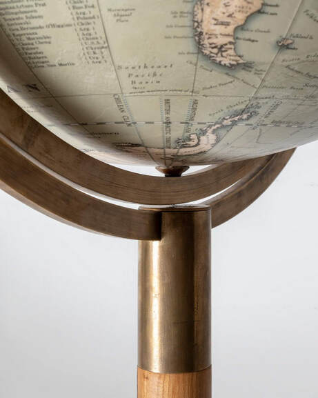 A globe from Lander and May, a brass arm holds a large globe that can be spun 360 degrees to show the South Pole. It is made using traditional techniques and materials