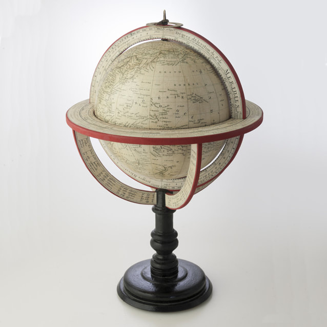old looking globe with a red ring around it, sitting on a black base