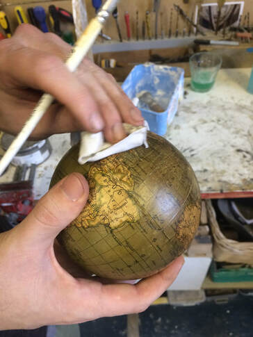 small globe being cleaned and restored, small green globe