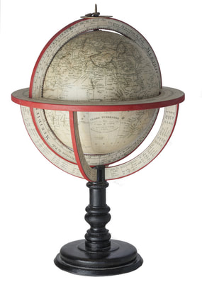 small antique globe within a red ring on a black wooden stand